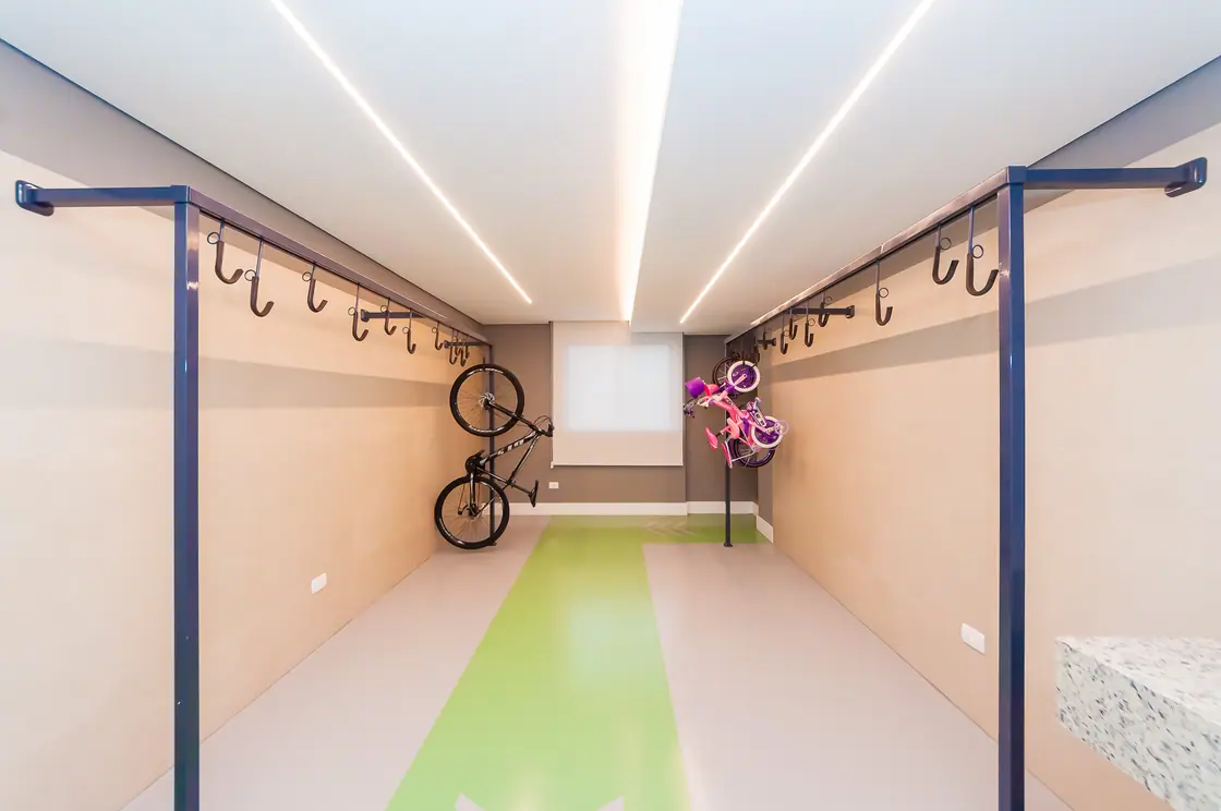 Bicicletário com suportes de parede, bancada de oficina e piso demarcado