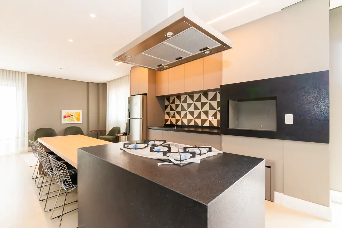 Espaço gourmet com ilha central, cooktop e coifa