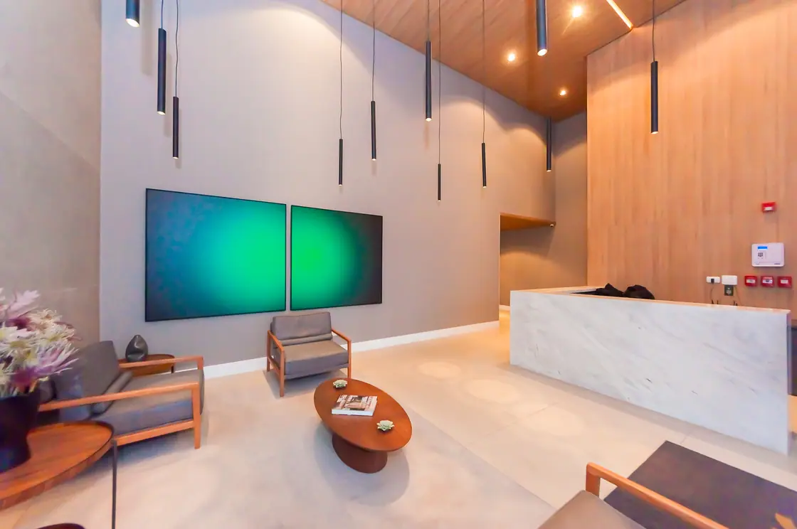 Hall social com balcão de mármore, poltronas e obra de arte