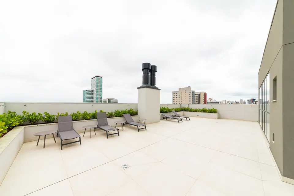 Solarium do ático com espreguiçadeiras ao sol e a cidade ao fundo