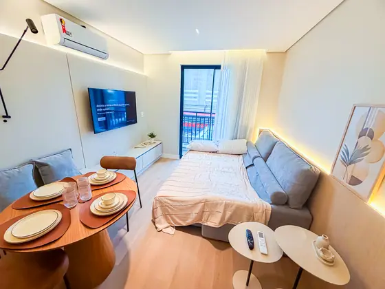 Apartamento de 1 quarto decorado, com cama, mesa e sofá integrados ao living